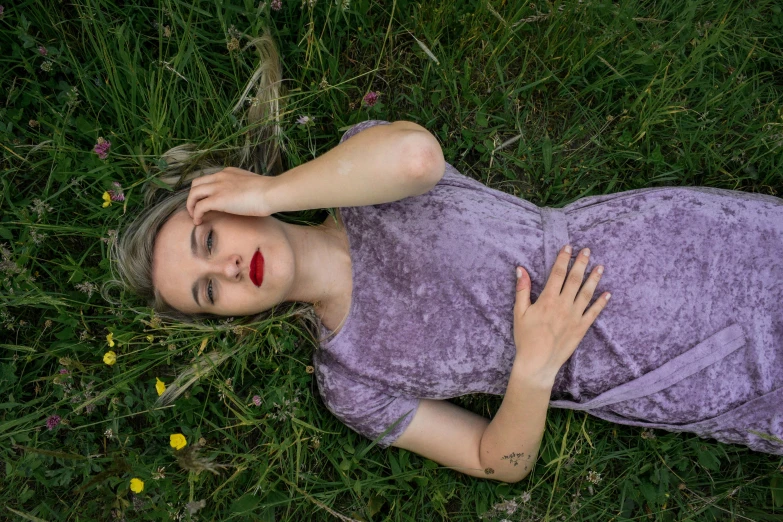 a person laying on top of the grass with their head near their face