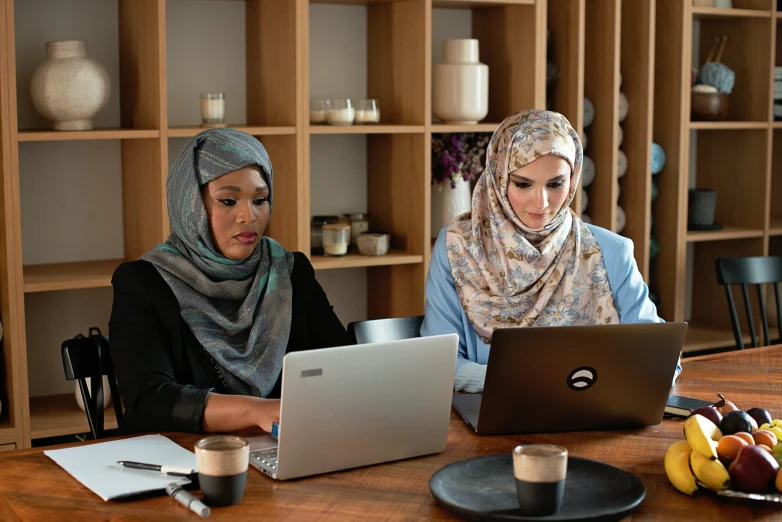 two women working on laptops at a desk