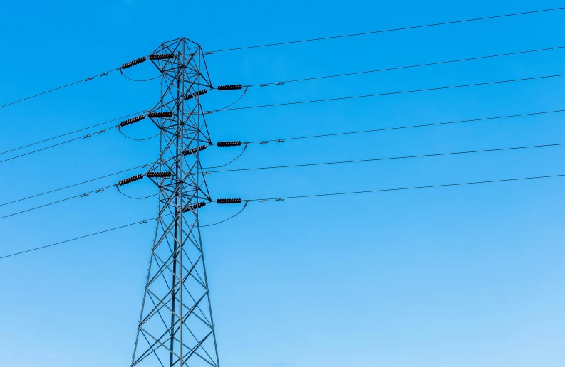 an electrical tower with multiple lines and some buildings