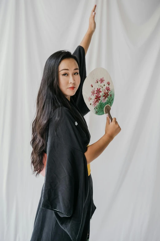 a woman with her hand in the air holding a fan