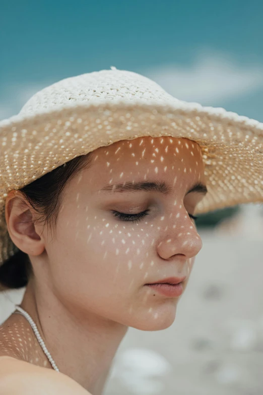 a woman wearing a hat and standing in the sand