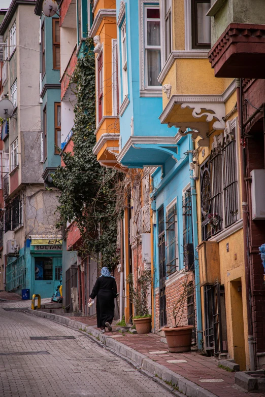 a woman is standing in an old street by the colorful buildings