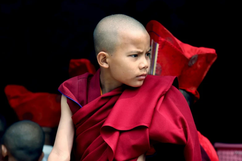 a child dressed in a monk costume with an umbrella behind him