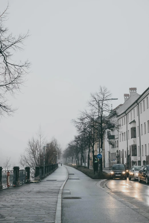 the street has cars driving down it in the rain