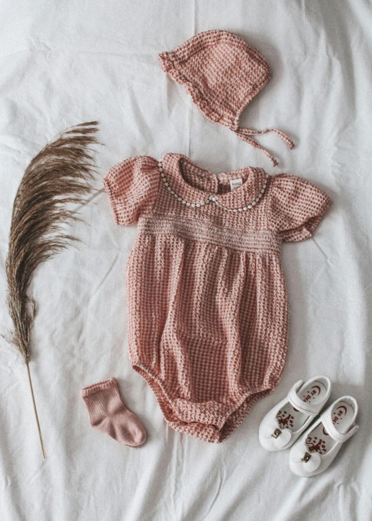 an infant's clothes and baby's shoes on top of a bed