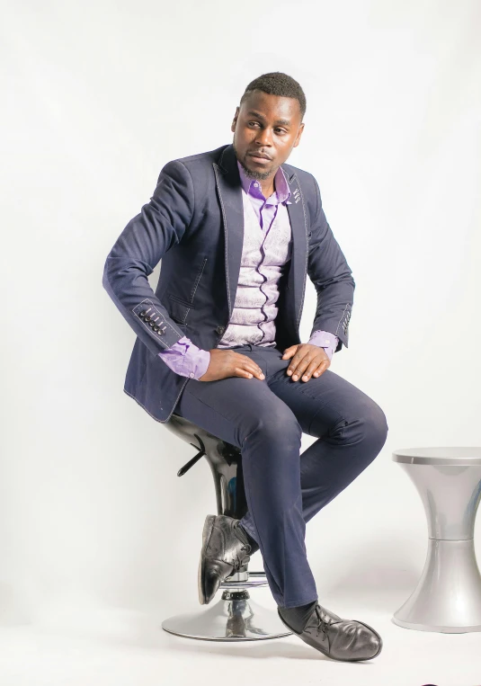 a man in a suit sitting on top of a stool