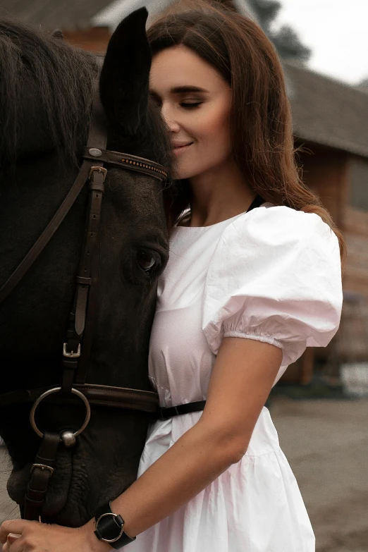 a woman holds her horse's bridle as it stands close to the camera