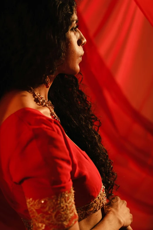 a women dressed in red is wearing a golden necklace