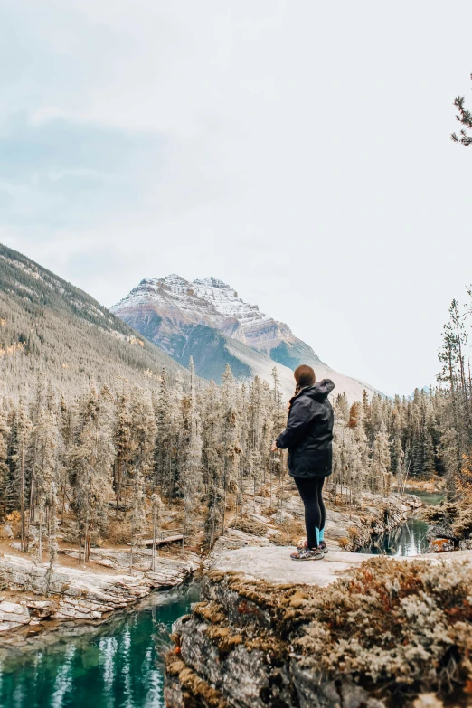 a man standing on top of a mountain next to a river