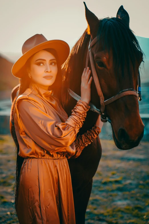 a woman in a long dress is touching the nose of a horse