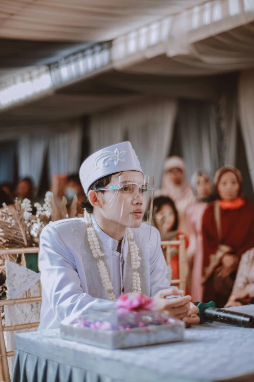 a man in white stands before a wedding ceremony