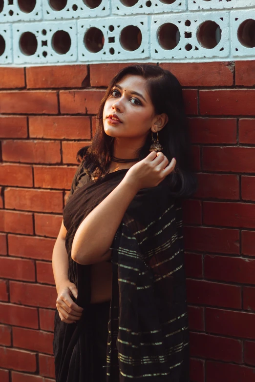 a young woman leaning against a brick wall and posing