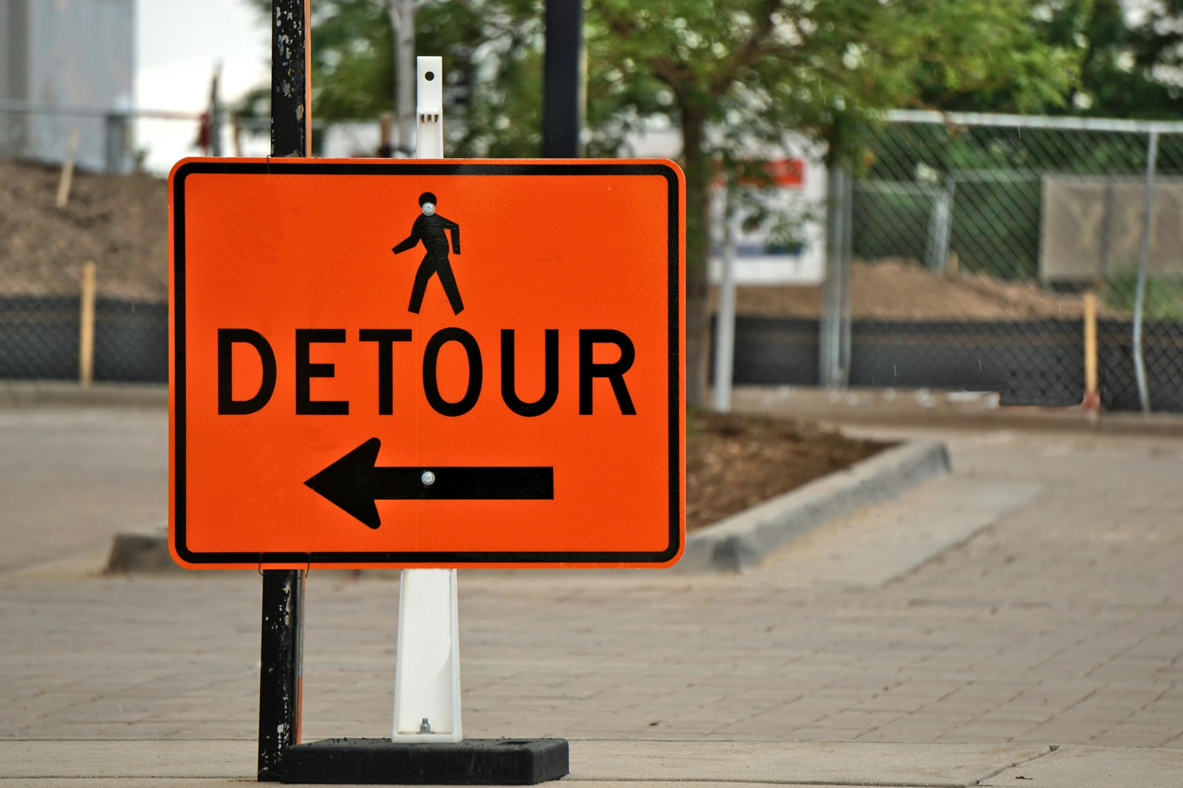 there is an orange detour sign on this sidewalk