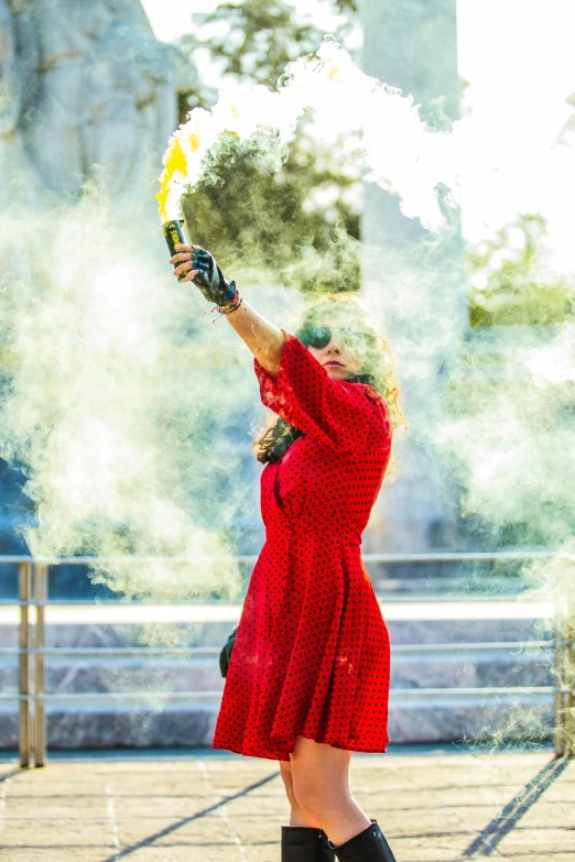 a woman in red dress throwing smoke out of her fingers