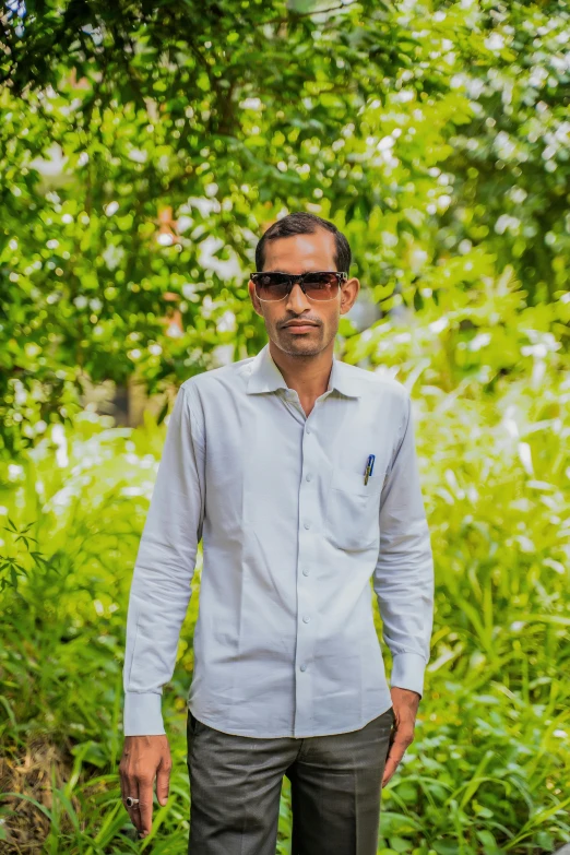 a man in white shirt standing by some trees