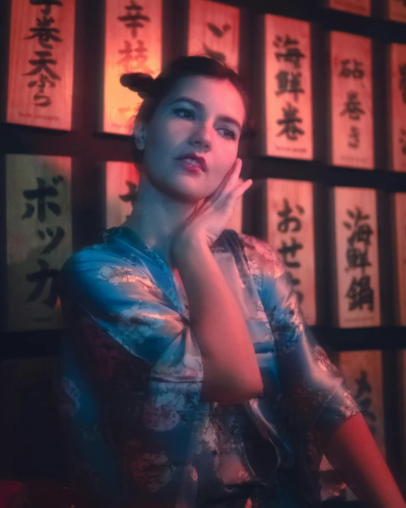 a woman wearing a shirt sitting in front of oriental writing