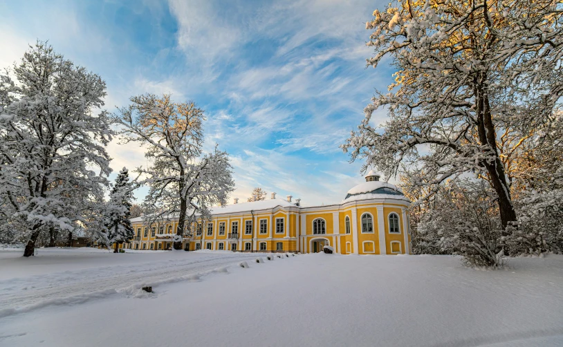 an ornate yellow mansion sits on a snowy slope