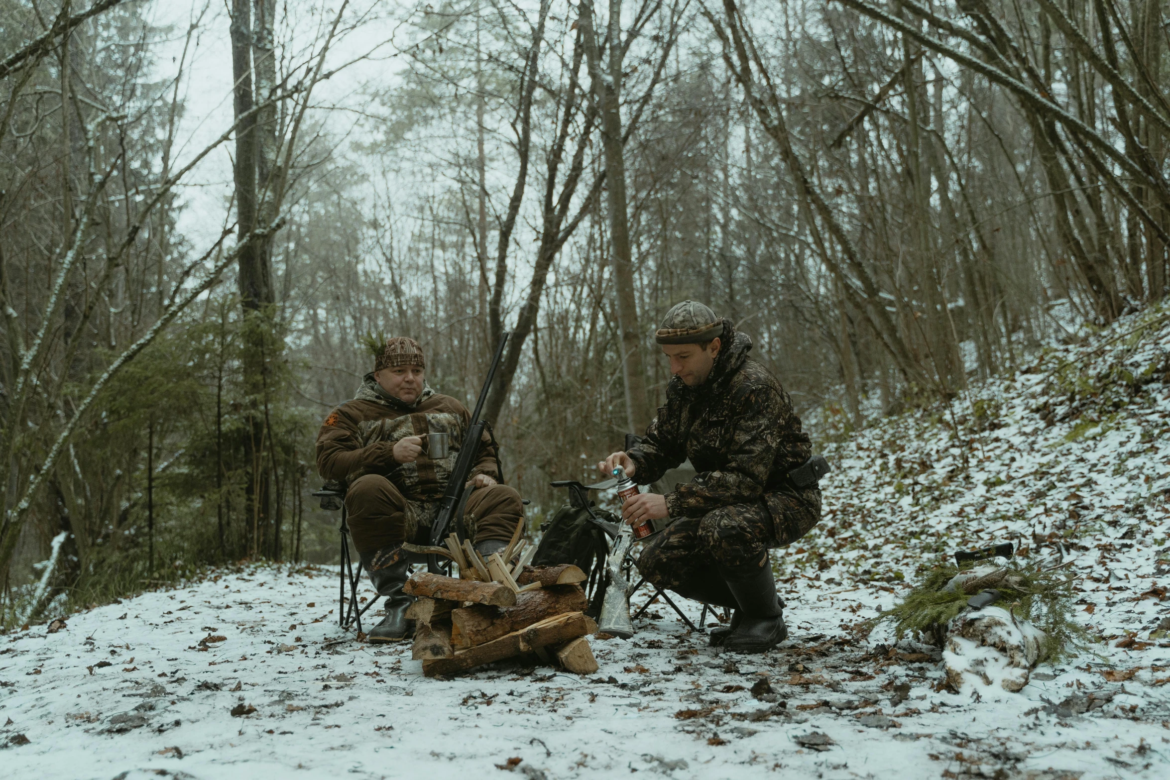 two men in jackets and sunglasses sitting next to a fire pit