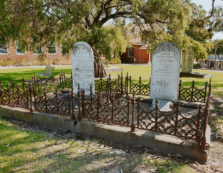 two headstones sit in iron fence in a cemetery