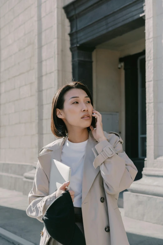 a woman holding up a white folder talking on the phone