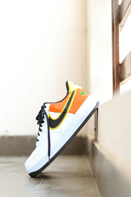 a pair of sneakers with a yellow, white, and orange design