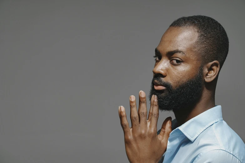 black man with beard and blue shirt blowing up finger