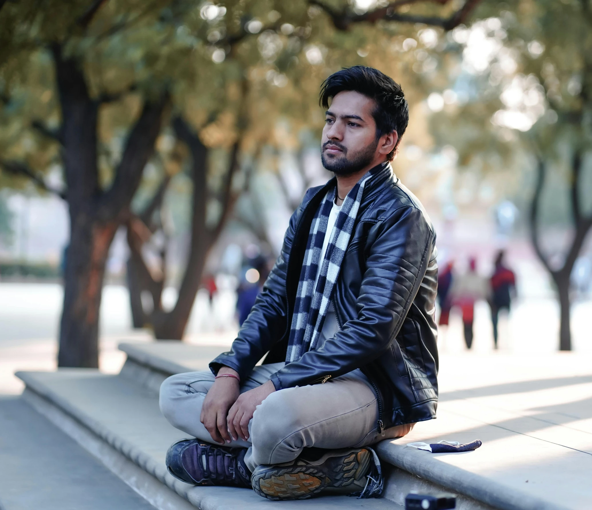 a man sits on the steps in a park with a black jacket