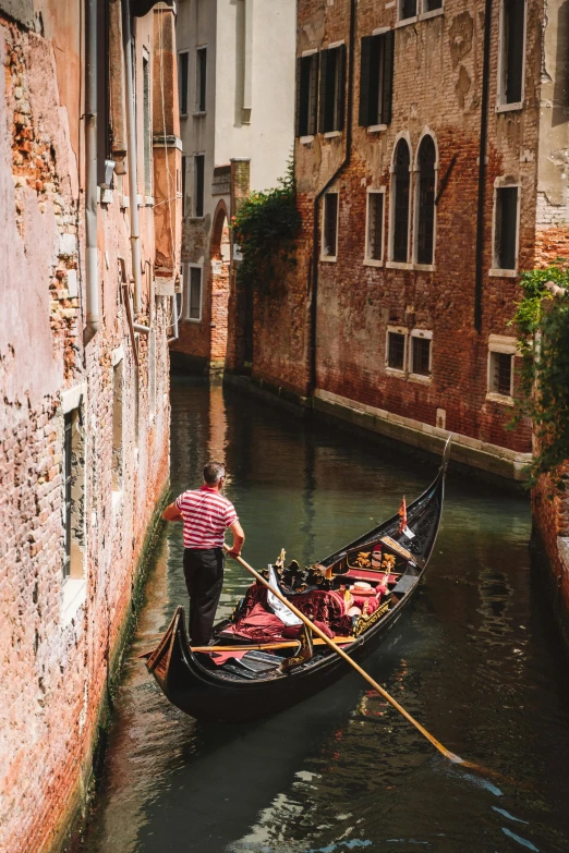 two people paddling their gondola through a narrow waterway