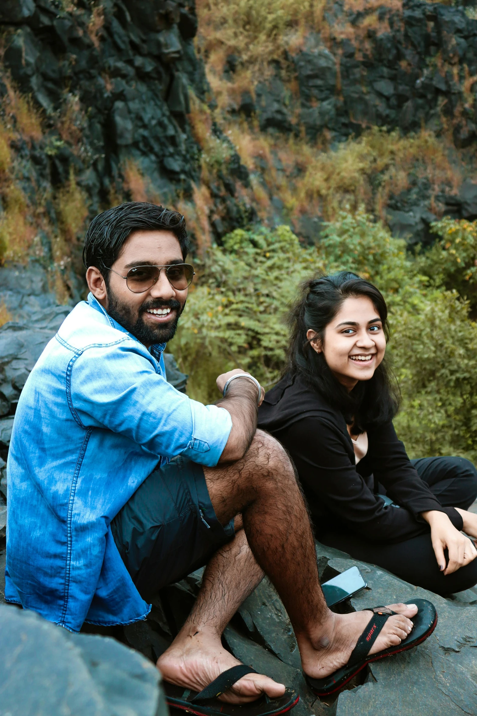 two people sitting on top of rocks near water