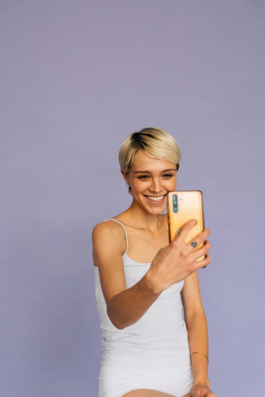 a woman poses for a po holding up a cell phone