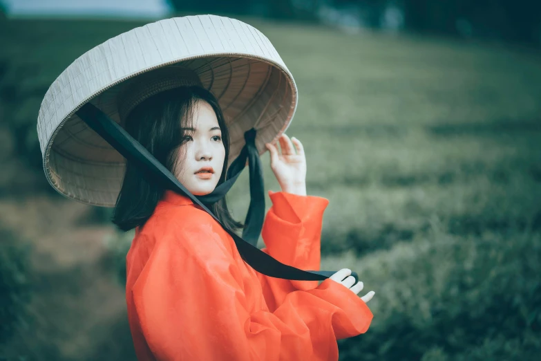 an oriental woman standing in a field with a hat on