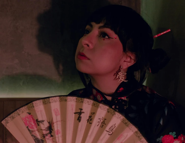 woman with oriental hair holding a white fan in a dark room