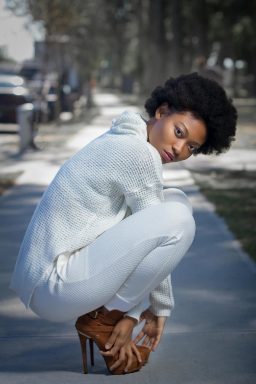 a black woman is crouching on a sidewalk