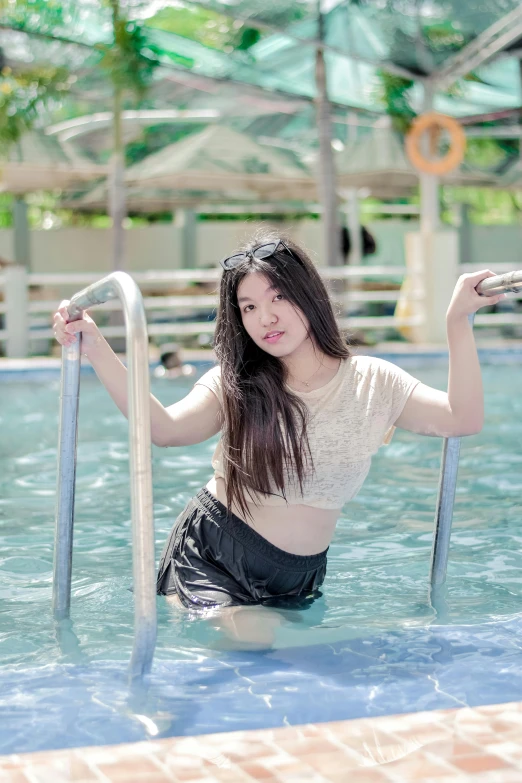 a woman in short shorts sitting next to a fence by a pool