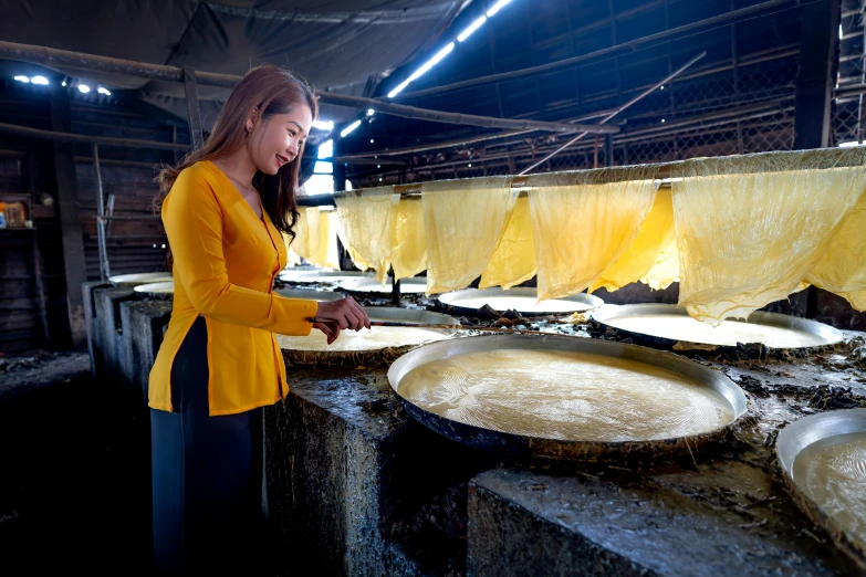 a woman working in a kitchen with several pans of food cooking