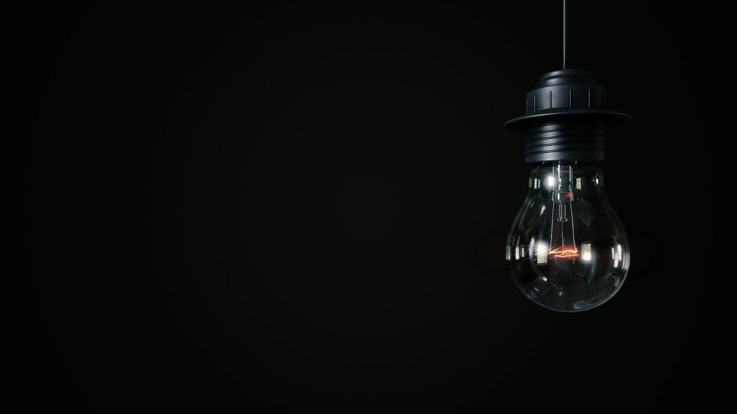 an old, glass lightbulb hanging on a black background