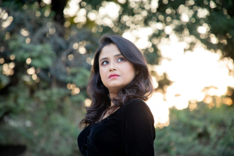 a woman in black shirt standing outside next to trees