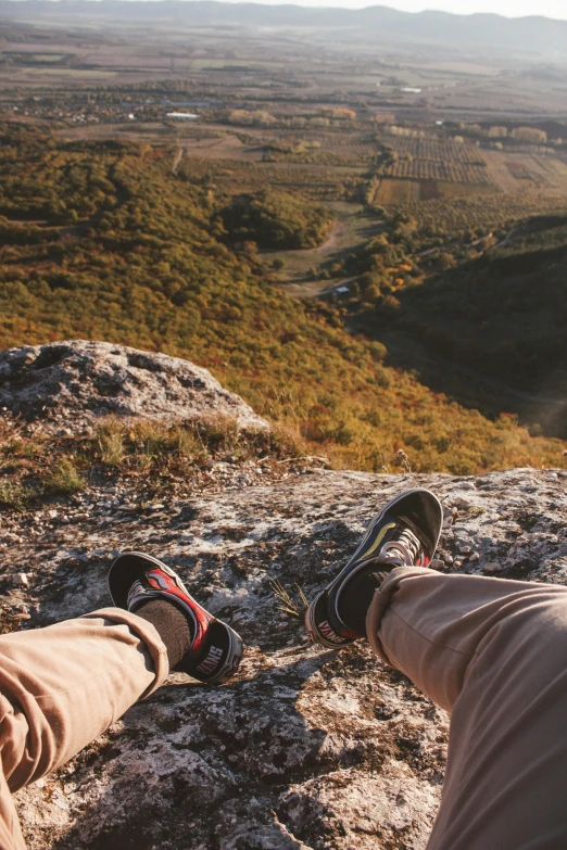 two people are sitting on a rock and looking over an open valley