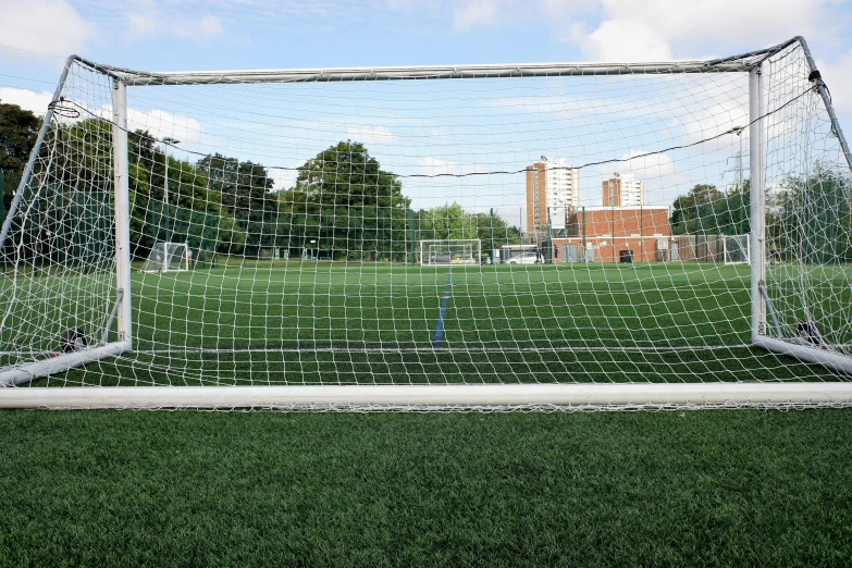 a goalie net at a field with a building in the background