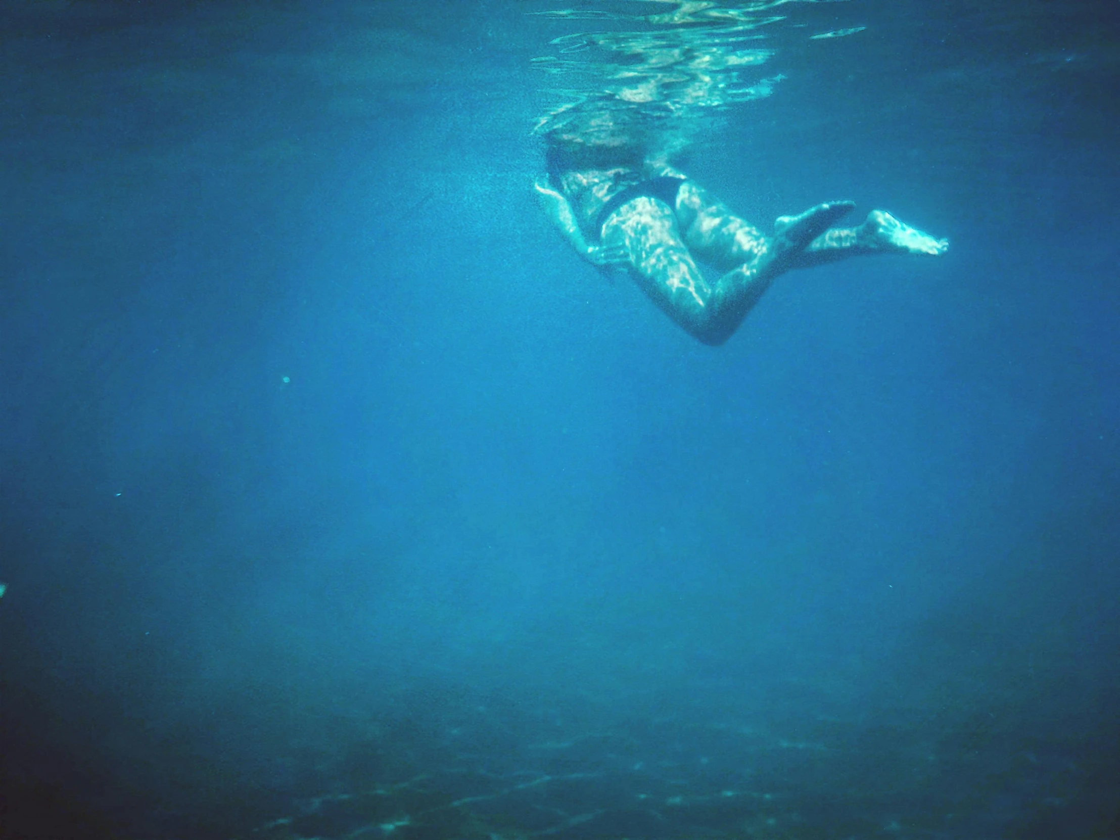 the person is swimming underwater in the blue water