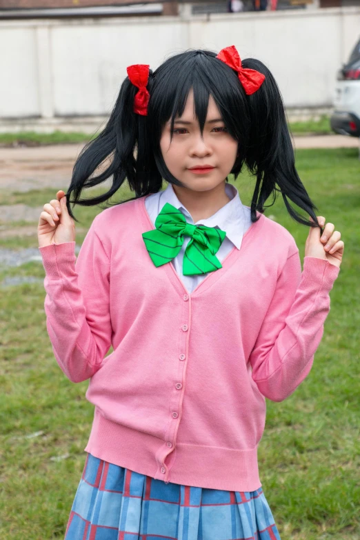 a girl in pink jacket and bow tie standing on grass