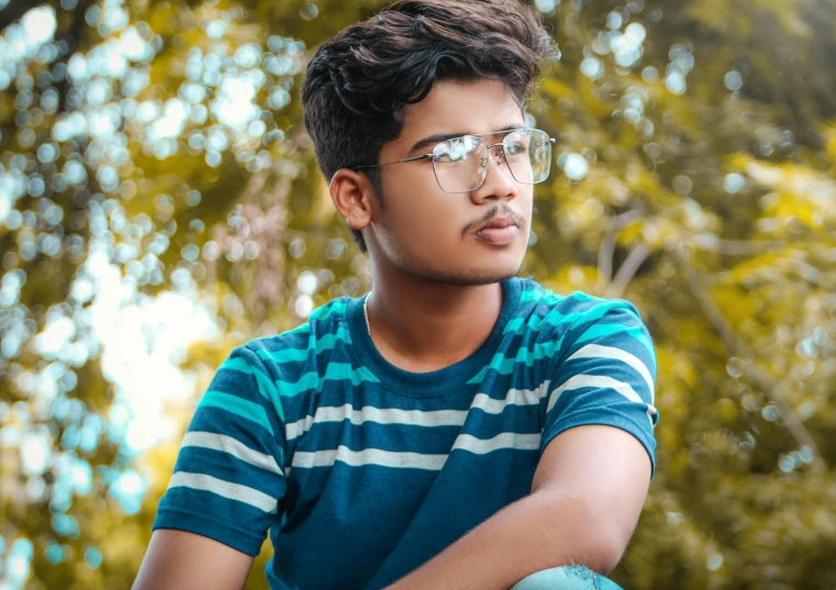 a young man wearing glasses is sitting down