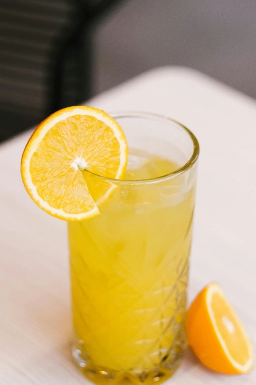 a tall glass with juice that has a lemon slice inside