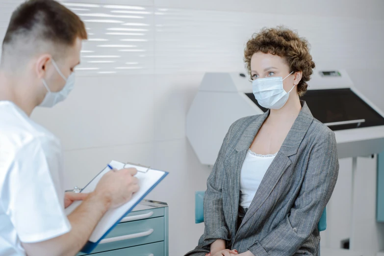 the woman in the medical mask is talking to another doctor