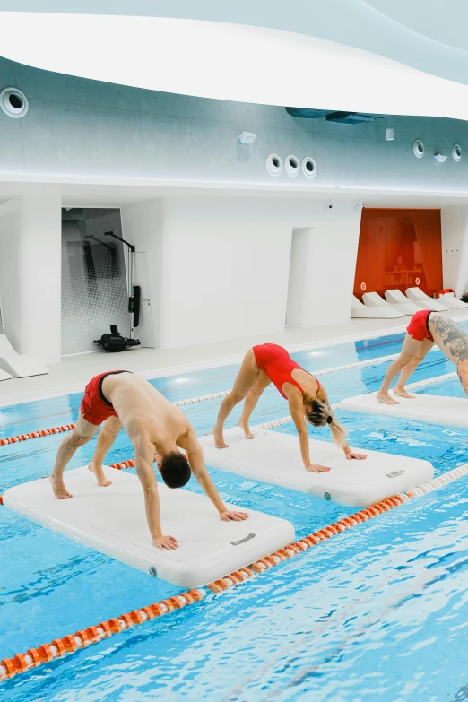 people in red and orange swimsuits practice on floating boards