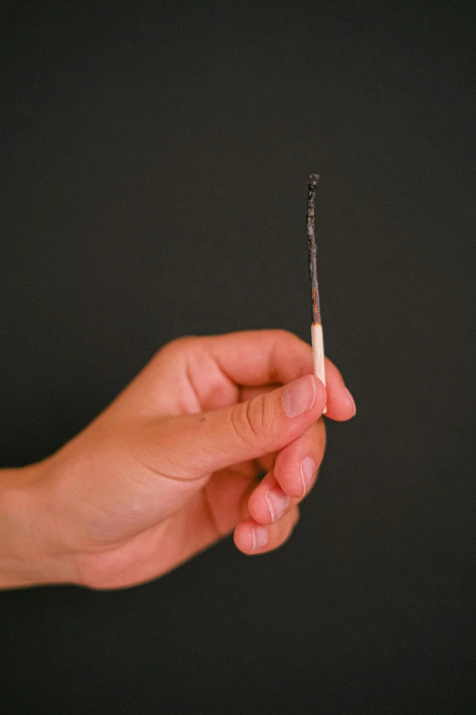 a person is holding a cigarette that has smoke coming out