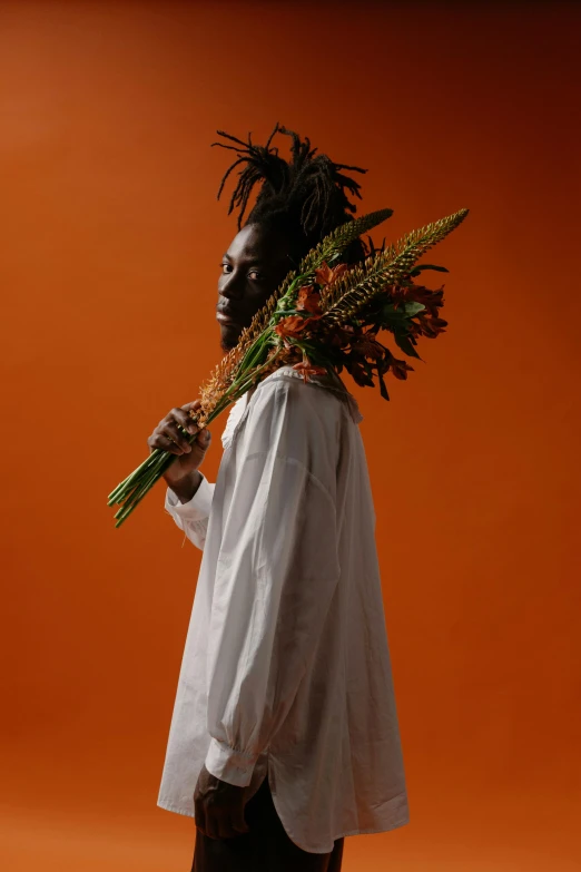 a man holding up two large plants that are wearing clothes