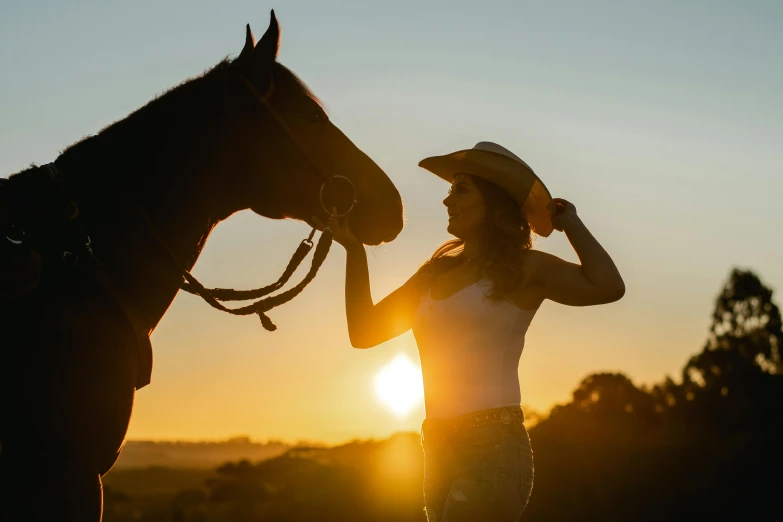 woman adjusting a hat as a horse watches