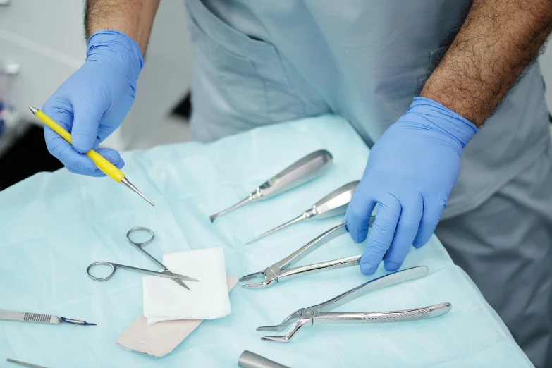 a surgeon in blue gloves holding an item and scissors