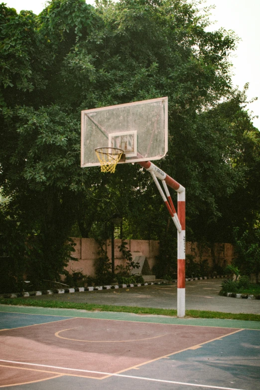 a basketball court and basketball hoop with trees in the background